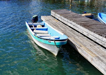 A small boat is moored to a wooden pier in Placencia, a fishing village near Havest Caye in Belize.
