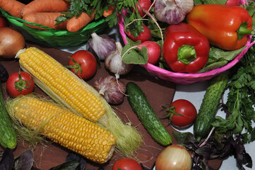 Ripe corn and fresh vegetables on a cutting board
