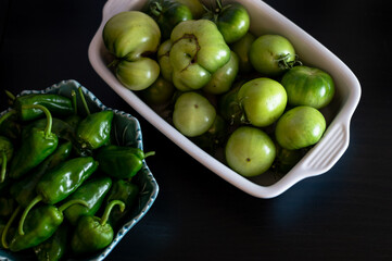 the last harvest of unripe padron peppers and tomatoes in bowls