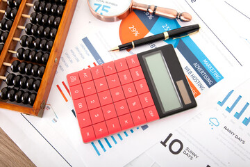 Calculator and abacus, magnifying glass and signature pen on business documents