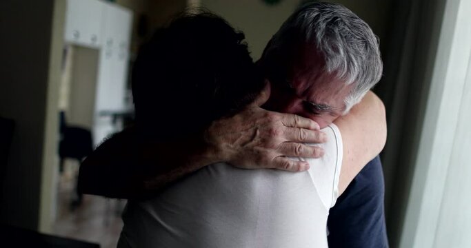 Senior man crying in wife shoulders
