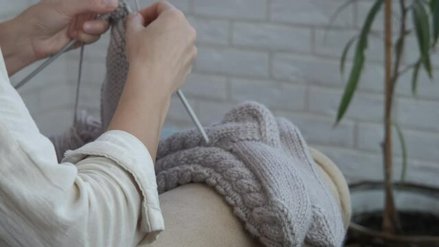 Handcraft socks. A woman's hand knit a yarn for socks in the room.