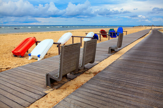 Touristic boats on the sandy beach . Walking path and bench on the seaside