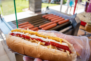 hot dog with mustard on hands