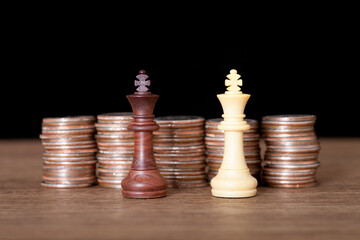 Two king chess pieces in front of a row of dollar coins