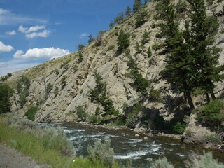 Yellowstone River flowing along the road and right next to a rocky mountain toward Gardiner, Montana.