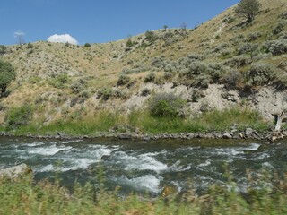 Close up of the Yellowstone River flowing along the road and right next to a rocky mountain toward Gardiner, Montana.