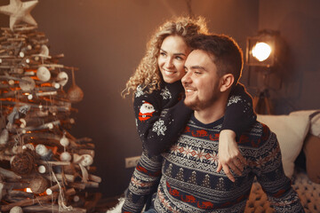 Couple near christmas tree. Lady in a black sweater. Family sitting on a bed.