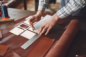 Man working with leather. Professional makes a wallet. erson measures the fabric.