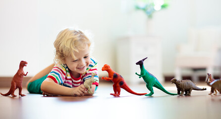 Child playing with toy dinosaurs. Kids toys.