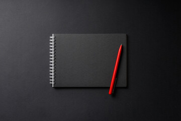 notebook with red pen on black background
