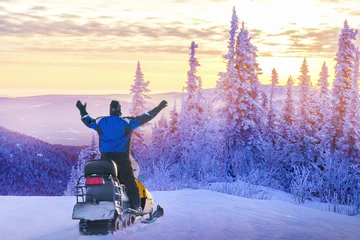 Fotobehang Man driving snowmobile in snowy forest. Concept freedom in winter travel. © Sergey