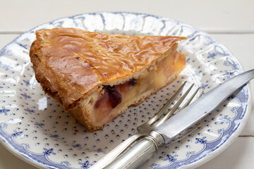 Traditional homemade apple pie with cranberries. Individual portion of the cake on a plate with cutlery on a wooden table