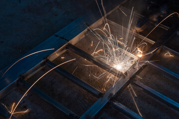 The welder is welding the parts of the iron door. The person working on a welder using an electric welding machine.
