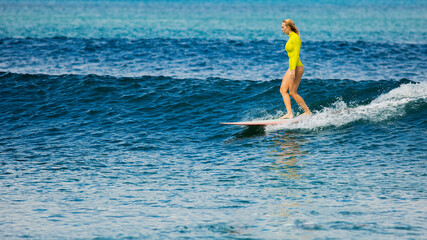 beautiful surfer girl rides a longboard