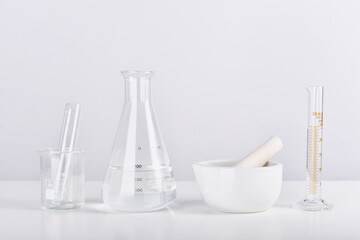 Group of scientific laboratory glassware and mortar with clear liquid solution, Research and...