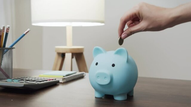 Young woman put coins in a piggy bank with saving money is investment for the future. Calculate income and expenses in daily life.