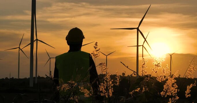 Engineers or workers with fields generating electricity at sunset and orange sky.