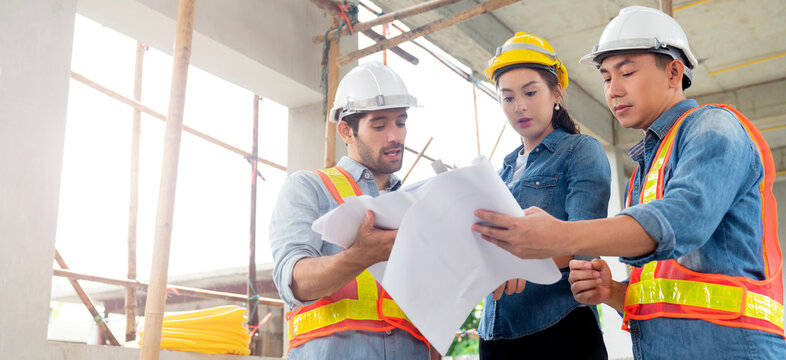 Young Asian Engineers Teamwork Site Inspector And Discuss Together Using Notebook Computer And Paper Blueprint At Building Construction Site.home Renovation Ideas Concept