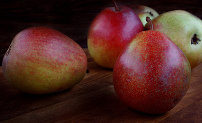 Several ripe pears lie on a wooden board.