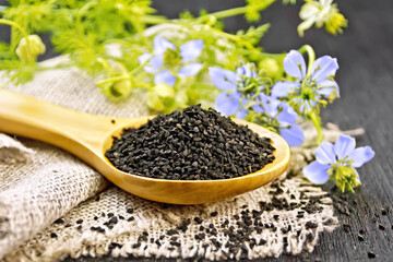 Seeds of black cumin in spoon on board