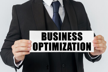 A businessman holds a sign in his hands which says - BUSINESS OPTIMIZATION