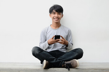 Portrait of a happy young asian man using mobile phone