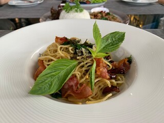 spaghetti with bacon and basil on table