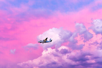 Fire fighting plane returning to base against a vivid pink sunset caused by wiildfire smoke