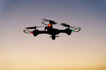Toy drone quad copter against sunset sky