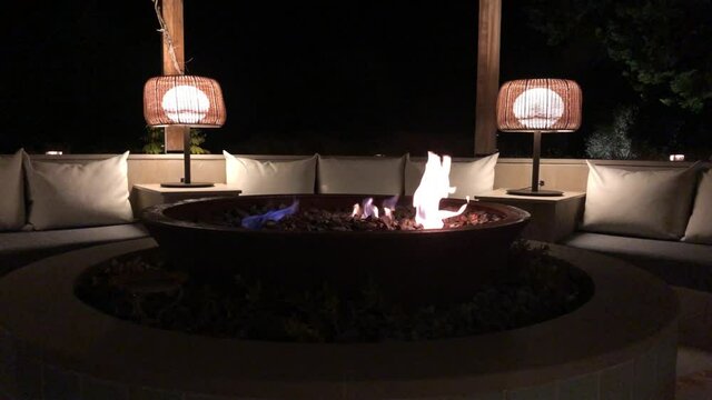 Close up view of a fire pit in front of a sofa. Shot of an exterior fireplace in an amazing outdoor site during night.