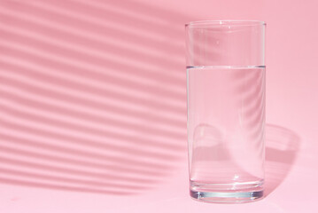 Glass of water on a pink background