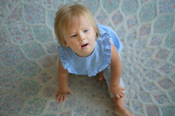 childhood, babyhood and people concept. happy little baby girl sitting on floor at home. view from above