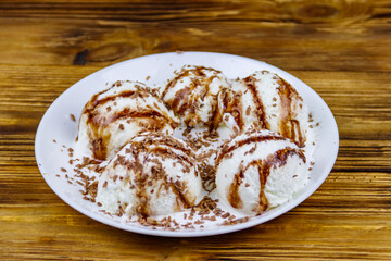 Vanilla ice cream with chocolate topping in white plate on a wooden table
