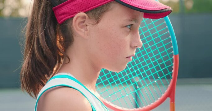 Close up portrait of cute athlete girl looking straight to camera, 4K. Cinematic shot of pretty teenage model with beautiful big bright blue eyes. Sweaty female sportsman with tennis racket on court