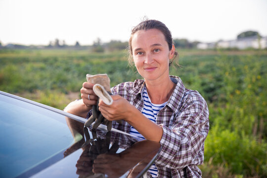 Confident woman farmer standing near car on farm outdoors