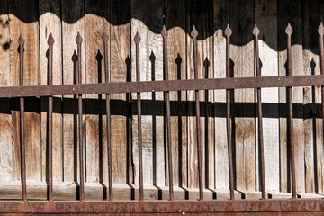 An old, rusty forged fence with spikes. The texture of a solid metal fence. 