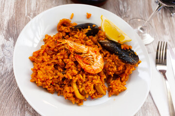 Traditional seafood paella with mussels, calamari and shrimps on white plate