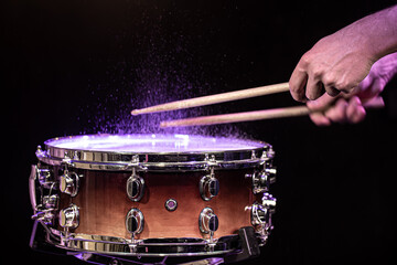 Fototapeta na wymiar Drum sticks hitting snare drum with splashing water on black background under studio lighting.