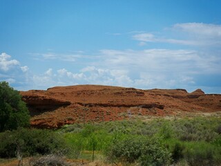 Red hills and green shrubs along the road, Wyoming landscape.