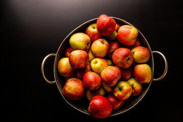 Ripe red apples in washtub on dark background top view