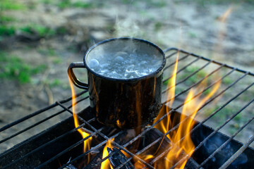 a mug of boiling water stands on a burning fire