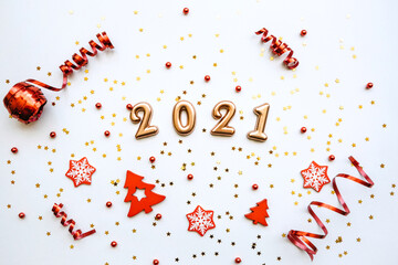 Gold numbers 2021 on a white background with confetti and various red holiday items. Christmas or New Year conceptual background.