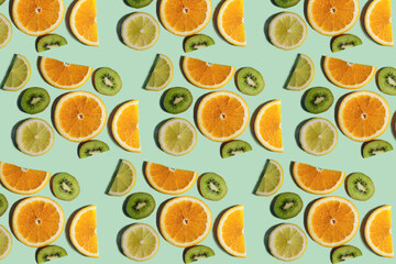 Fruit pattern. Repeating slices of kiwi, lemon and orange on a light green background. Bright fruit pattern made from natural fruits. Horizontal. The concept of healthy food and vegetarianism.