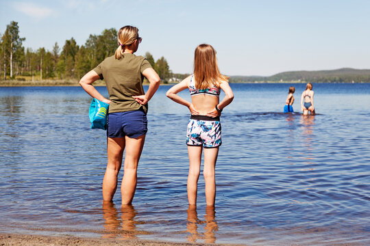 Umea, Norrland Sweden - June 21, 2020: mother and daughter stand by the shore and look out over the lake