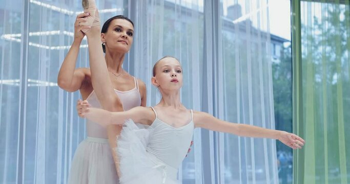 Positive Teacher Former Ballerina Helps Little Girl Raise Long Leg Into Splits Standing By Window At Studio Training Slow Motion