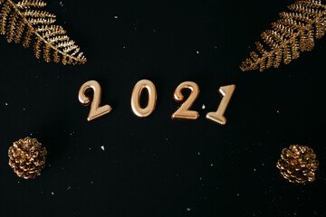 Gold numbers 2021 and golden trinkets on dark or black backgrounds. Christmas or New Year background.