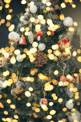 Christmas tree decoration festive background. Various toys and baubles and holiday lights on the tree.