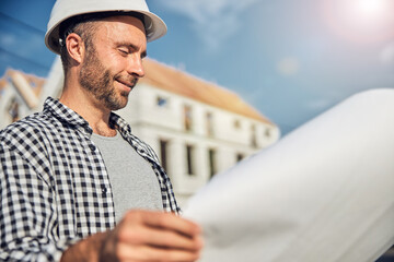 Gladsome man looking closely at a white sheet of paper