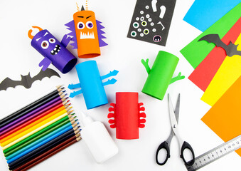 Halloween decoration. DIY and kids creativity concept. Step by step instructions: make a monster from a roll of colored paper toilet paper. Step 7 glue the hands to the body.